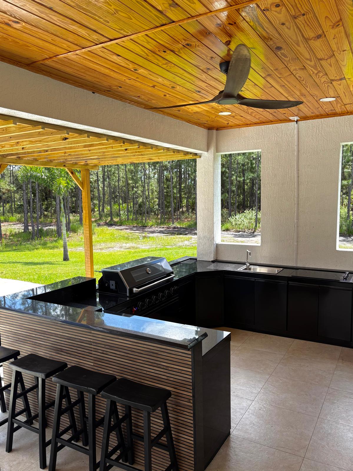 Covered outdoor kitchen with wood ceiling and fan