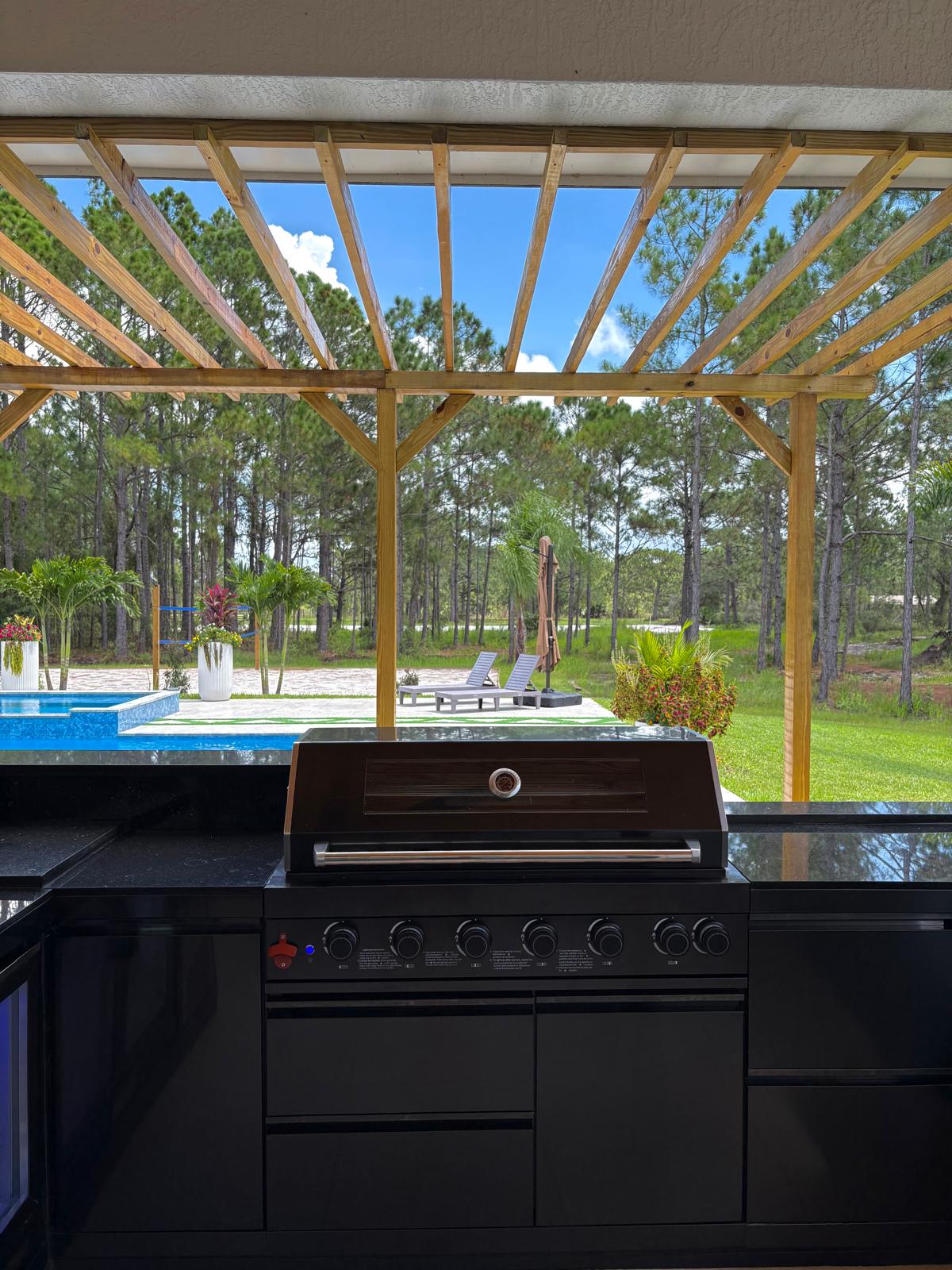 Outdoor kitchen with built-in grill and dark granite countertops