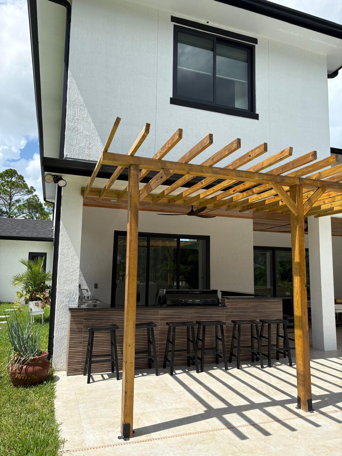 Outdoor kitchen with wood-slat bar and pergola exterior view